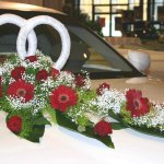 2 Trauringe als Symbol der Hochzeit im Blumengesteck. Diese Variante eignet sich besonders gut für die Fahrzeuge mit großen Motorhauben.